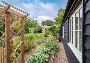 einen Garten mit einer hölzernen Pergola neben einem Haus in der Unterkunft Woodland Lodge in Wilby