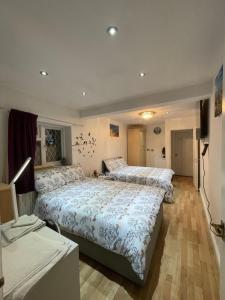 1 Schlafzimmer mit 2 Betten und einem TV in der Unterkunft North Avenue, Guest House, Heathrow Airport-Free Parking in Hayes