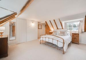 a white bedroom with a bed and a window at Holly Cottage in Westleton