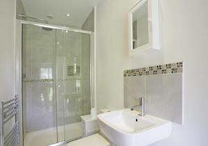 a white bathroom with a sink and a shower at The Stables in Friston