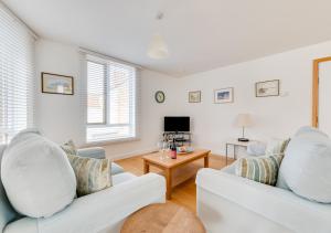 a living room with two white couches and a table at Osprey in Southwold