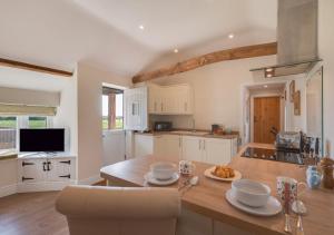 a kitchen with white cabinets and a wooden table at Marlborough House Forge in Saxtead