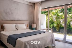 um quarto com uma cama e uma grande janela em Qavi - Flat rua principal vista jardim #ÎledePipa em Pipa