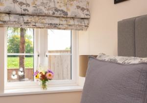 a bedroom with a window with a vase of flowers at Marlborough House Forge in Saxtead