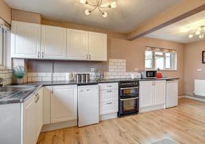 a large kitchen with white cabinets and wooden floors at Barn Owl Retreat Sibton in Sibton