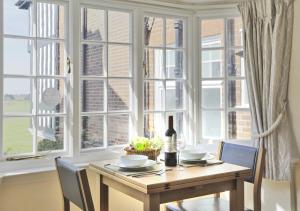 a table with chairs and a bottle of wine in front of a window at Far View Two in Southwold