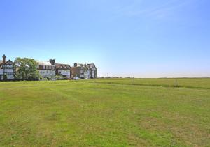 un gran campo de césped con casas en el fondo en Far View Two en Southwold