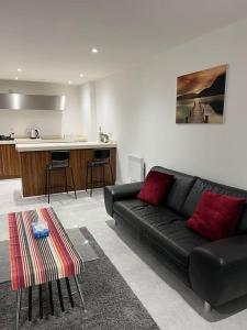 a living room with a black couch and a table at Orion building apartments ,OPOSITE GRAND CENTRAL,FREE CAR PARK in Birmingham