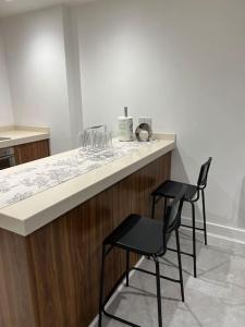 a kitchen with two bar stools at a counter at Orion building apartments ,OPOSITE GRAND CENTRAL,FREE CAR PARK in Birmingham