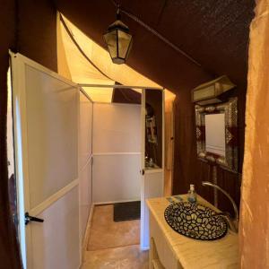 a bathroom with a white door and a sink at Fabulous Desert Camp in Merzouga