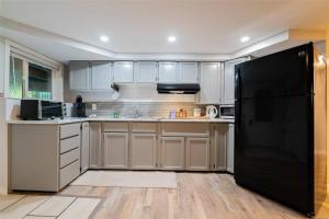 a kitchen with white cabinets and a black refrigerator at Trails End Beach House suite with hot tub and beach bedroom cabin! in Ladysmith