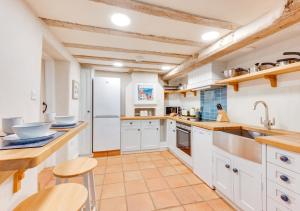 a large kitchen with white cabinets and wooden ceilings at Sparrows Nest in Harkstead
