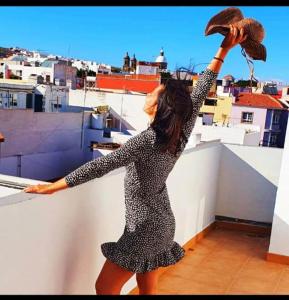 Una mujer parada en una cornisa con la mano en el aire en Apartamento Villa Alpispa, en Agüimes