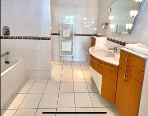 a white bathroom with a tub and a sink at Promenade House in Douglas