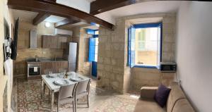 a kitchen with a table and a couch in a room at Traditional Townhouse In The Hearth Of Valletta in Valletta