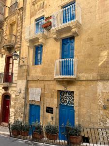 a building with blue doors and balconies on it at Traditional Townhouse In The Hearth Of Valletta in Valletta
