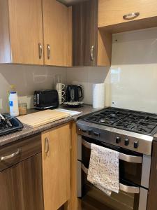 a kitchen with a stove top oven and wooden cabinets at Impeccable 4-Bed Caravan in Clacton-on-Sea in Clacton-on-Sea