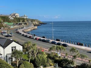 a road with cars parked on it next to the ocean at Promenade House in Douglas