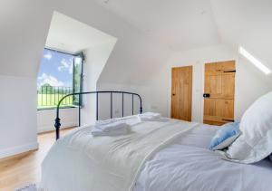 a white bedroom with a large bed with a window at The Green Shed in Sudbourne