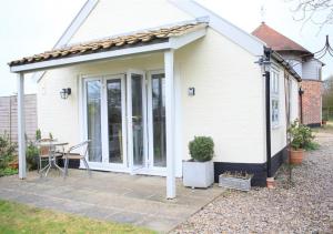 a white house with a patio with a table at Garden Cottage The Old Mill in Snape