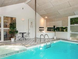 a swimming pool in a house with a table and chairs at 12 person holiday home in Glesborg in Fjellerup Strand