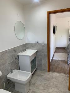 een badkamer met een toilet, een wastafel en een spiegel bij PURA VIDA 2 in Mar de las Pampas