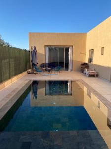 a swimming pool in front of a house at Ennakhil Garden in Marrakech
