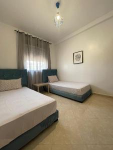 a bedroom with two beds and a table and a window at Joli appartement au centre d'Oujda in Oujda