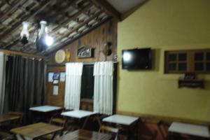 Pousada Marumbe في ماكاكوس: غرفة مع طاولات وتلفزيون على الحائط