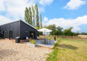 a black building with a table and an umbrella at The Cowshed in Crowfield