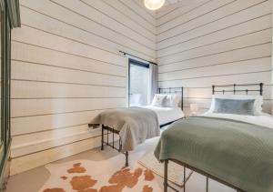 Duas camas num quarto com paredes de madeira em The Cowshed em Crowfield