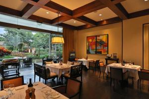 a restaurant with white tables and chairs and a large window at InterContinental Costa Rica at Multiplaza Mall, an IHG Hotel in San José