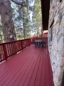 a red deck with a table and bench on it at Sherwood Arms Motel in Running Springs