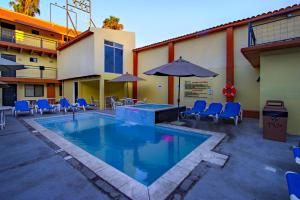a pool with chairs and umbrellas next to a building at La Pinta Hotel in Ensenada