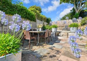 a patio with a table and chairs and purple flowers at 2 Bryn Hyfryd in Llanbedrog