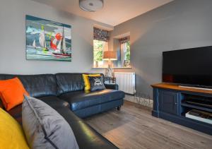 a living room with a black leather couch and a flat screen tv at 2 Bryn Hyfryd in Llanbedrog