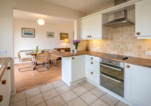 a kitchen with white cabinets and a table and a dining room at 15 Lon Cernyw in Abersoch
