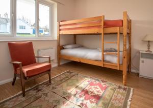 a bedroom with two bunk beds and a chair at 15 Lon Cernyw in Abersoch
