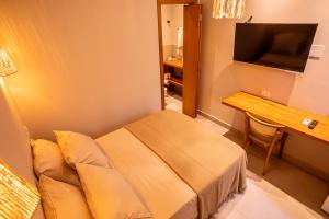 a hotel room with a bed and a desk and a television at Casa Savana in São Paulo