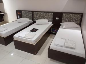 two beds in a hotel room with white sheets at Hotel Flert - Tatuapé in Sao Paulo