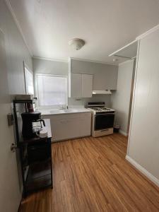 a kitchen with white cabinets and a wooden floor at Sherwood Arms Motel in Running Springs