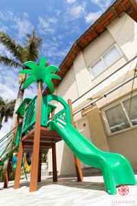 um parque infantil com um escorrega verde em frente a uma casa em Hotel Geranius Ingleses em Florianópolis