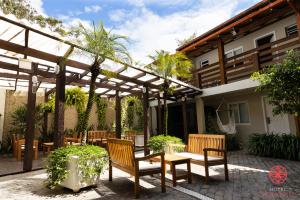 a patio with wooden chairs and a pergola at Hotel Geranius Ingleses in Florianópolis