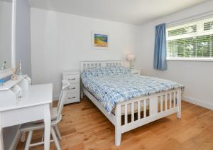 a white bedroom with a bed and a desk at 4 Glyn y Marian in Llanbedrog