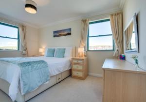 a bedroom with a bed and two windows at 32 St Brides Bay View Apts in Broad Haven