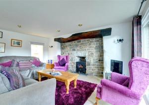 a living room with purple furniture and a stone fireplace at 3 Tyn Llan in Dyffryn