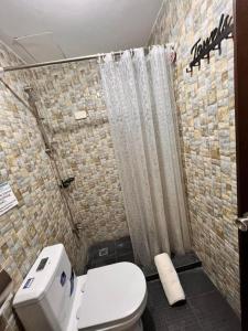 a bathroom with a toilet and a shower curtain at Cabuhat Duco Lodge 1 in Naic