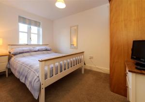 a bedroom with a bed and a flat screen tv at 5 Afon y Felin in Abersoch