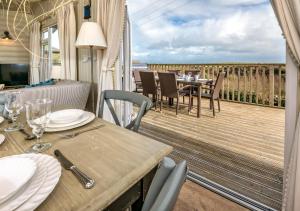 a dining room with a table and chairs on a deck at 9 Braich Farm in Llanengan
