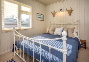 a bedroom with a white bed with blue sheets and antlers on the wall at 9 Braich Farm in Llanengan